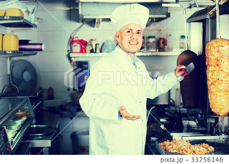 mature chef slicing kebab in fast food. 33756146