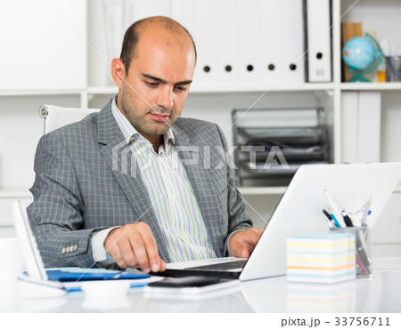 Cheerful businessman in suit working at the computer Cheerful businessman in suit working at the computer 33756711