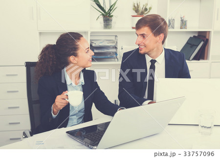 young man and cheerful woman coworkers talking in firm office 33757096
