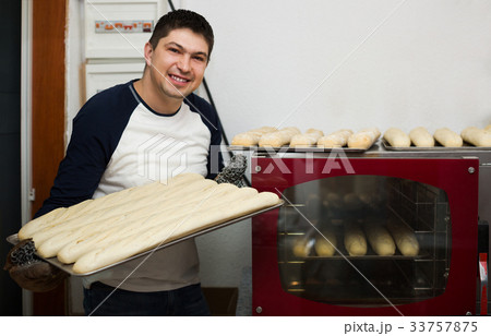 Smiling man baking fresh bread Smiling man baking fresh bread 33757875