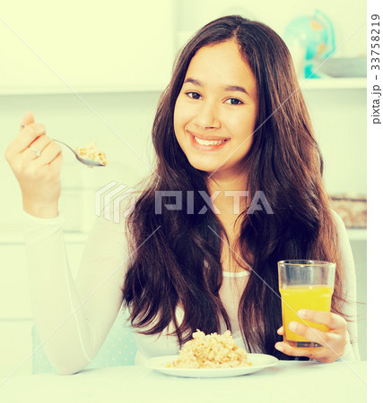 smiling girl eating cereals and drinking juice 33758219