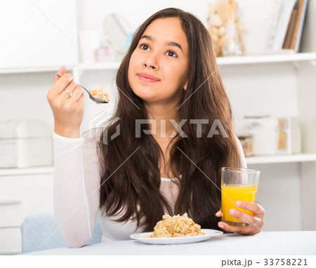 smiling girl eating cereals and drinking juice smiling girl eating cereals and drinking juice 33758221