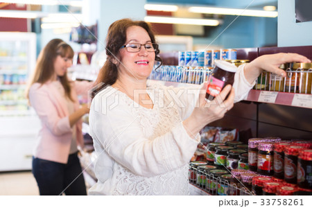 Women choosing confiture in food store. 33758261