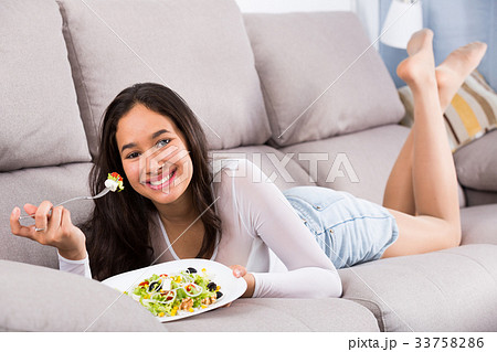Young smiling girl eating tasty salad 33758286