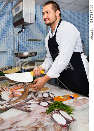 Man behind counter cut off piece of fish Man behind counter cut off piece of fish 33758516
