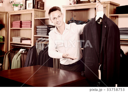 Male shopping assistant offering various cloths 33758753
