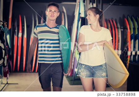 Positive couple is ready for surfing on colorful boards Positive couple is ready for surfing on colorful boards 33758898