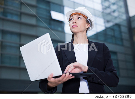 Smiling female designer in suit and hat with folder is exploring project 33758899