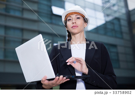Smiling woman architector in suit and hat is exploring project in her laptop Smiling woman architector in suit and hat is exploring project in her laptop 33758902