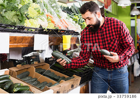 Positive male seller holding cucumbers in store Positive male seller holding cucumbers in store 33759186