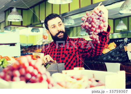 Shop assistant demonstrating grapes Shop assistant demonstrating grapes 33759307