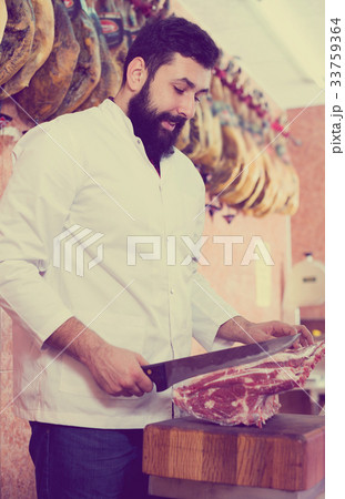 Male shop assistant carving meat Male shop assistant carving meat 33759364