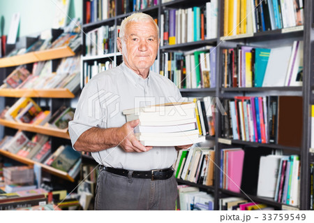 Mature man is showing books that he bought Mature man is showing books that he bought 33759549