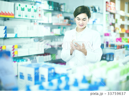 female pharmacist checking assortment of drugs in pharmacy female pharmacist checking assortment of drugs in pharmacy 33759637