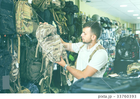 Man choosing textile backpack gun in military shop 33760393