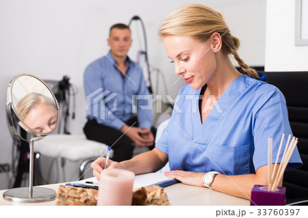 Female doctor is writing the conclusion about result of examination of client 33760397