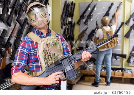 Male customers try on ammunition with weapon 33760459