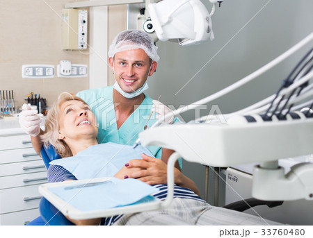 Male dentist treating female patient 33760480
