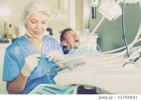 Dentist in dental clinic with patient behind Dentist in dental clinic with patient behind 33760691