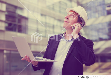 Smiling worker talking at mobile phone Smiling worker talking at mobile phone 33760809