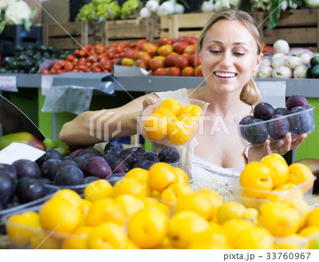 young woman buying plums at market. young woman buying plums at market. 33760967