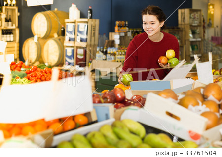 Portrait of cheerful brunette girl buying apple in supermarket Portrait of cheerful brunette girl buying apple in supermarket 33761504