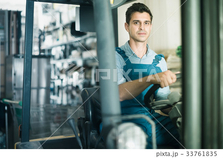concentrated man in unifom is using сargo moving machine in the building store 33761835