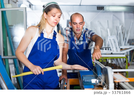 Craftsman is explaining work on circular saw to young worker woman Craftsman is explaining work on circular saw to young worker woman 33761866