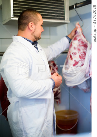 Adult male shop staff cutting sirloin at top 33762029