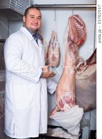 Happy male shop staff cutting sirloin at top 33762037