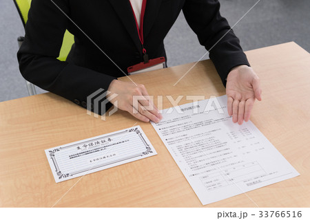 カウンターで意向確認書を説明する女子社員 33766516