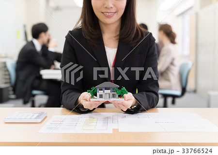カウンターで住宅模型を持つ女子社員 33766524