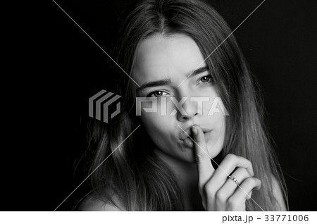 The girl with long hair holds finger near the lips The girl with long hair holds finger near the lips 33771006