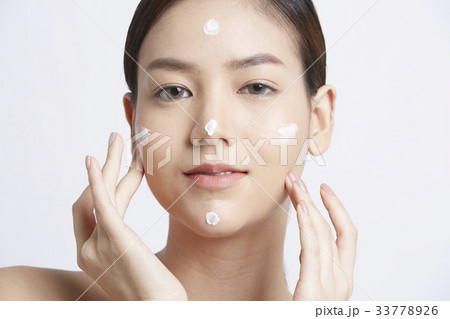 a girl is applying cream on her face and smiling a girl is applying cream on her face and smiling 33778926