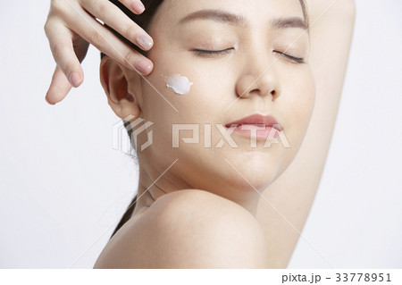 a girl is applying cream on her face and closing her eyes a girl is applying cream on her face and closing her eyes 33778951
