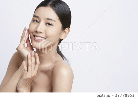 an attractive girl is touching her face and smiling 33778953