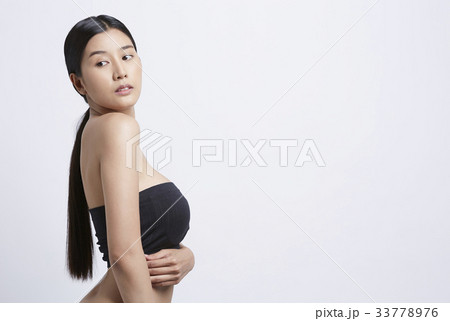 young woman with long hair is wearing black tank top and looking away 33778976