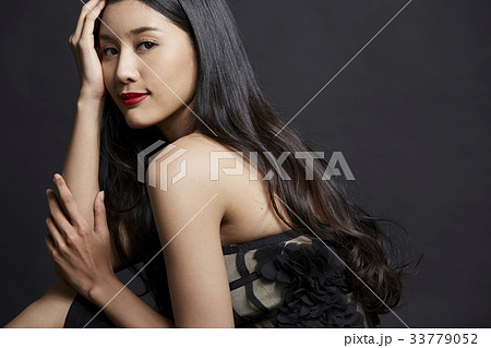 portrait of woman holding her face and smiling on black background 33779052