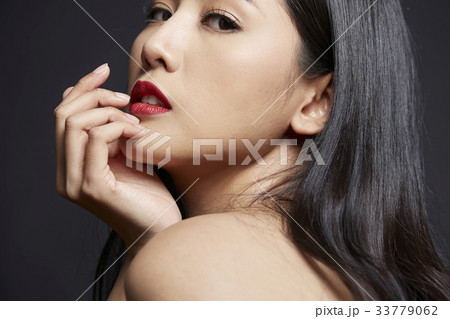 portrait of woman touching her face and looking at camera 33779062