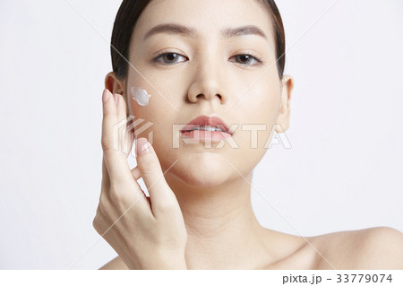 portrait of woman applying cream and looking at camera 33779074