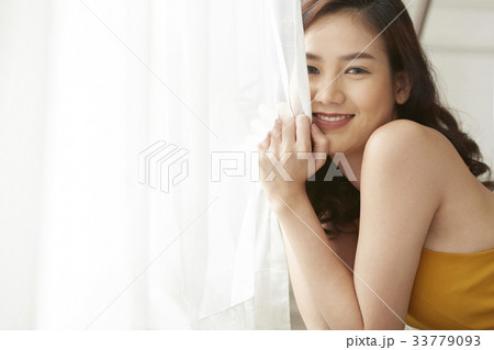 pretty girl is holding curtain and smiling pretty girl is holding curtain and smiling 33779093