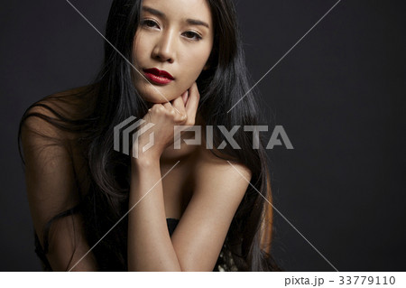 portrait of beautiful woman holding her chin and looking at camera on black background 33779110