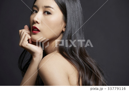 A beautiful girl is touching her chin with hand on black background 33779116