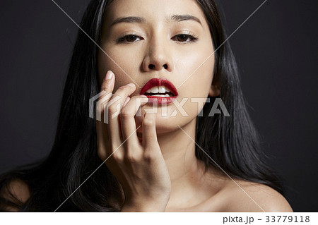 A girl with long black hair and red lips is posing photo on black background A girl with long black hair and red lips is posing photo on black background 33779118