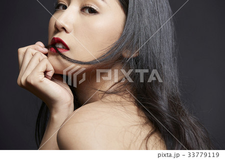 A sexy beautiful girl is touching her chin with a hand on black background A sexy beautiful girl is touching her chin with a hand on black background 33779119
