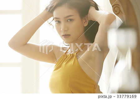 A Thai girl is raising arms and touching hair in her room 33779169
