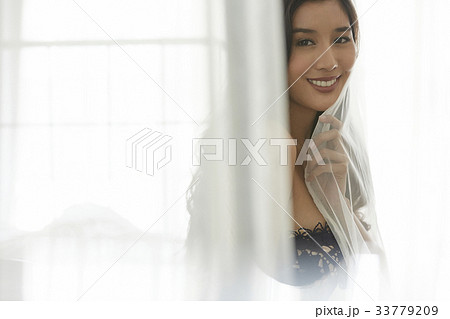 The picture of girl smiling and holding the curtain 33779209