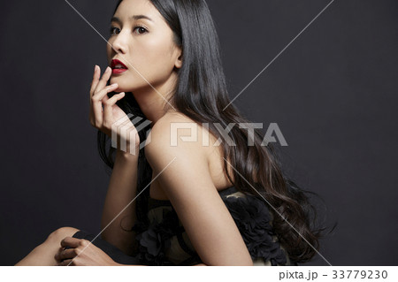 The picture of girl sitting and putting the fingers on her lips on black background 33779230