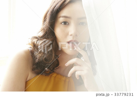 portrait of a girl leaning on the curtain and touching her lip 33779231