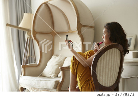 portrait of beautiful woman sitting on a chair and making up inside. 33779273